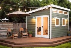 a small backyard shed with patio furniture and an umbrella over the door, sitting on a deck