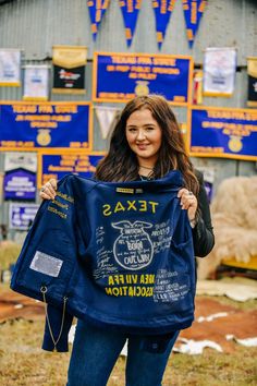 a woman holding up a blue t - shirt with the words texas written on it