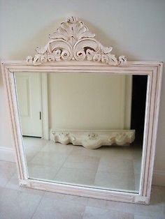 an ornate white mirror sitting on top of a tiled floor