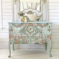 an ornate painted dresser with a mirror on top