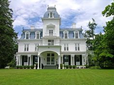 a large white house sitting on top of a lush green field