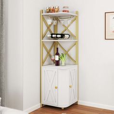 a white and gold shelving unit with wine glasses on the top, next to a potted plant