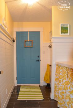 a blue door in a yellow and white bathroom with a rug on the floor next to it