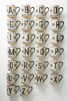 many coffee mugs are stacked on top of each other with letters and numbers in them