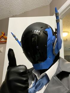 a man in a suit and tie wearing a blue mask with his hand up to the side