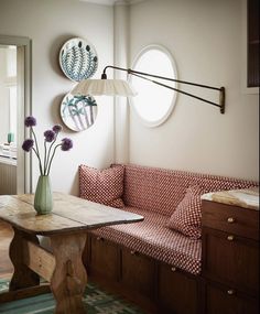 a wooden table sitting next to a couch in a living room under two circular windows