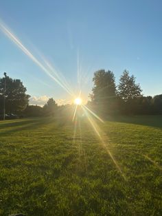 the sun shines brightly over a grassy field