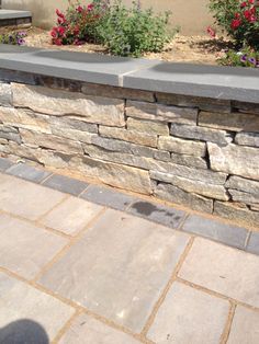 a stone wall with flowers in the background