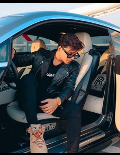 a young man sitting in the back seat of a blue car with his foot propped up