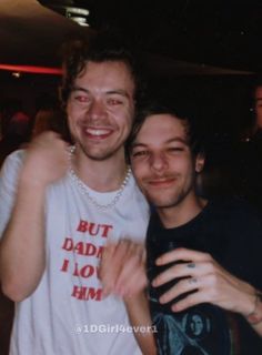 two young men standing next to each other smiling at the camera with their arms around one another