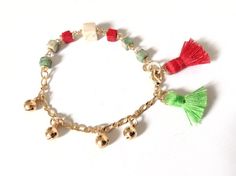 "Christmas Bell Bracelet This delicate 6.05\" boho bracelet is made with 5mm square natural stone beads, twisted by hand with gold filled wire. On one side of the bracelet, it has five tiny bells that ring to move and ends up with two delicate 1cm tassels red and green color reminiscent of Christmas. It is a customizable perfect layering piece for Christmas season. A solid gold plated lobster clasp makes for easy and secure closure and a gold plated extension chain makes the bracelet adjustable Adjustable Tassel Bracelets As Gifts, Bohemian Green Bracelets For Festive Occasions, Tassel Bracelet Jewelry Gift, Adjustable Tassel Jewelry For Festive Occasions, Adjustable Bohemian Jewelry For Holiday, Bohemian Adjustable Bracelets For Holiday, Bohemian Style Adjustable Holiday Bracelets, Bohemian Adjustable Bracelets For Festive Occasions, Bohemian Round Bead Bracelets For Holiday