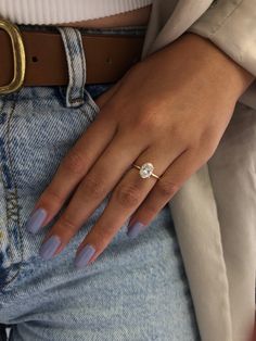 a woman's hand wearing a ring and jeans