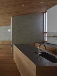 a kitchen with wooden cabinets and black counter tops next to a large wall mounted sink