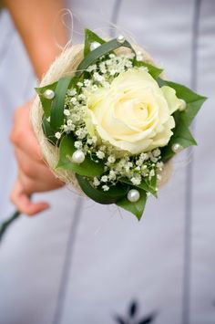 a woman holding a white rose and baby's breath flower bouquet in her hand