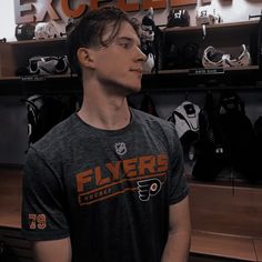 a young man standing in front of a display of hockey equipment and helmets on shelves