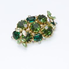 Hobe Green Crystal Brooch. Rare Hobé 1950’s brooch, gold tone with green crystals. Approximate Measurements: Length 2.6", Width 1.6" Made in: USA Condition: Very Good About The Designer Hobé jewelry is highly sought after by collectors of costume jewelry worldwide. The story begins with Hobé Cie, a fine jewelry line in France founded in 1887 by goldsmith Jacques Hobé in France. The costume jewelry division was added 40 years later by his son. Today, when costume jewelry collectors think of Hobé, Green Brooch For Party, Green Brooch Jewelry For Evening, Green Evening Brooch Jewelry, Vintage Green Brooch For Party, Green Costume Jewelry Brooch For Collectors, Vintage Green Brooch For Evening, Vintage Green Evening Brooches, Vintage Green Evening Brooch, Antique Costume Jewelry