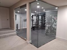 a home gym with glass walls and treadmills in the center, on carpeted flooring