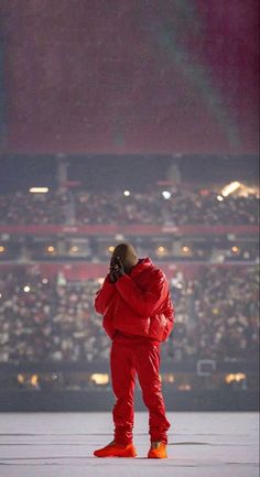 a man in red is standing on the stage talking on his cell phone while wearing bright orange sneakers