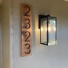 a house number sign mounted to the side of a wall next to a light fixture