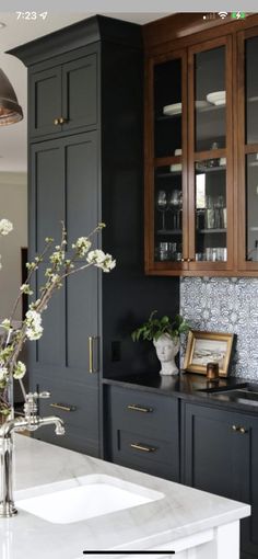 a kitchen with black cabinets and white counter tops, flowers in vases on the sink