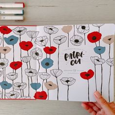 a hand holding an open notebook with poppies on it