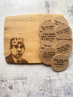 a cutting board with four coasters on it and a drawing of a man's face