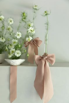 two vases filled with flowers and tied ribbons