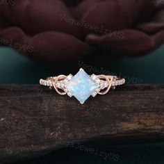 a white opal and diamond ring on top of a piece of wood