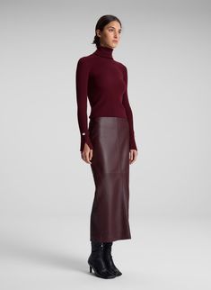 The Jett Top is crafted from stretch merino wool in a burgundy hue. This long-sleeve silhouette features a foldover turtleneck and two sleek slits placed along the sleeves. This style runs true to size. Shop Tops. Styling Tip: Wear with tailoring for the day and a fluid skirt to transition to evenings. Burgundy On Burgundy Outfit, Leather Skirt Design, Burgundy Tops For Women, Burgundy Sweater Vest Outfit, Casual Winter Outfits Skirt, Brown Leather Maxi Skirt Outfit, Wine Colored Outfits, Long Leather Skirt Outfit Winter, Eggplant Outfit