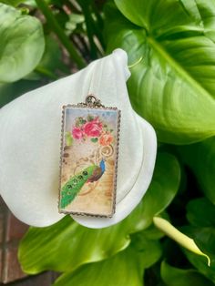 a close up of a flower with a bird on it's back drop necklace