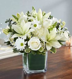 a vase filled with white flowers on top of a wooden table