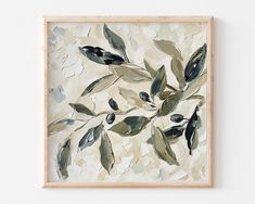 an abstract painting with green leaves on a white background in a wooden frame hanging on the wall