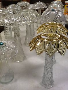 several glass vases are lined up on a table with white clothed tables in the background