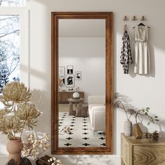 a mirror sitting on the side of a wall next to a dresser and potted plant