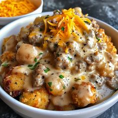 a white bowl filled with potatoes covered in gravy and topped with cheddar cheese