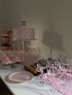 a table topped with lots of pink cake and wine glasses