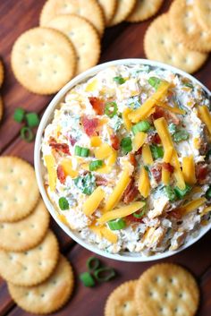 a white bowl filled with cheese and crackers on top of a table next to crackers