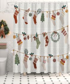 a christmas themed shower curtain with stockings and ornaments hanging on a line next to a toilet