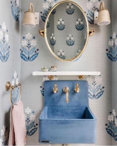 the bathroom is decorated with blue and white wallpaper, gold faucets and an ornate mirror