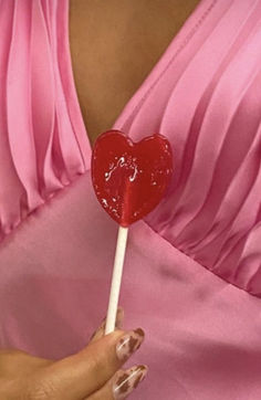 a woman in a pink dress holding a lollipop with a heart on it