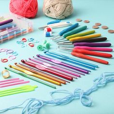 there are many crochet hooks and knitting needles on the blue table with balls of yarn