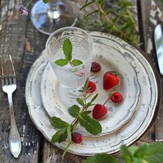 strawberries and raspberries are placed on a white plate with silverware next to it