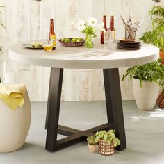 a table with plates and glasses on it in front of some potted planters