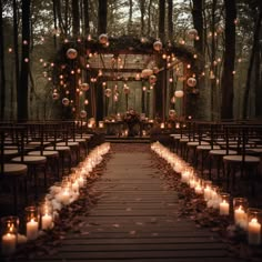 an outdoor wedding setup with candles and lanterns on the aisle, surrounded by trees in the background