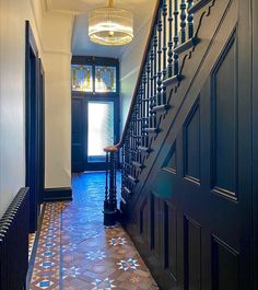 the hallway is decorated with blue and brown tile, along with an ornate stair case