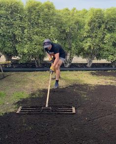 a man is digging in the dirt with a shovel and wearing a black t - shirt