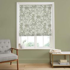 a living room with green walls and a window covered in roman blind shades that have flowers on them