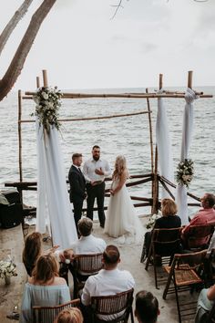 a bride and groom standing at the end of their wedding ceremony on the beach with an ocean view behind them