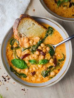 two bowls of soup with bread and spinach