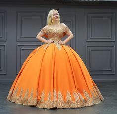 a woman in an orange ball gown posing for the camera with her hands on her hips